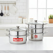 Two Max Fresh stainless steel steamers with glass lids on white kitchen counter with utensils and jars in background